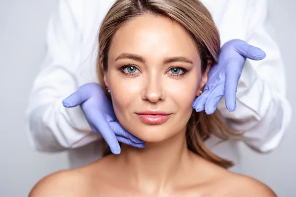 Close up of a woman's face with a doctor wearing rubber gloves standing behind her holding his hands around her face to show the amazing Botox treatment from ProCare Wellness Institute in Virginia Beach.