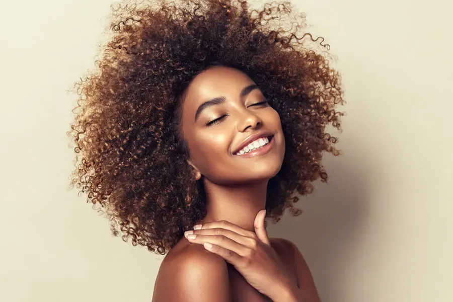 A black woman touches her beautiful smooth skin happily after receiving chemical peel treatments from ProCare Wellness Institute in Virginia Beach.
