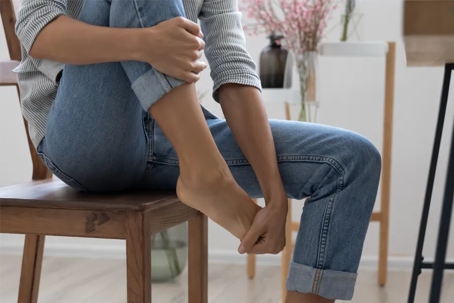 A woman sits and rubs her aching foot. Get treatment for Diabetic Neuropathy from ProCare Wellness Institute in Virginia Beach.