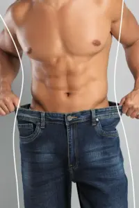 Semaglutide-Weight-Loss-Treatment A strong shirtless man in jeans holds the waistlines of his too-big jeans to show the success of semaglutide weight loss from ProCare Wellness Institute in Virginia Beach.