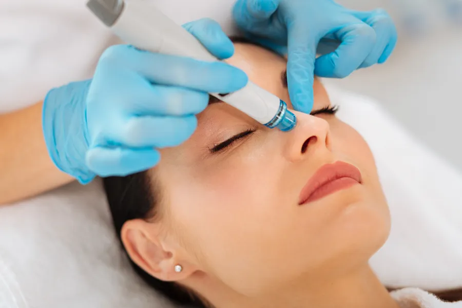 A woman receives a facial with a hydrafacial device. Schedule HydraFacial treatments from ProCare Wellness Institute in Virginia Beach.