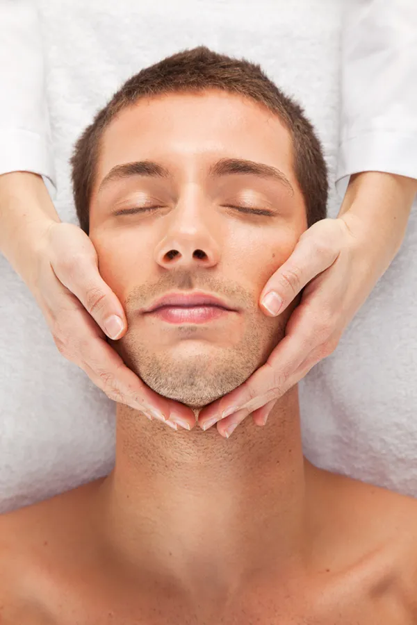 Close-up of a man with a clinician's hands on his face, receiving a HydraFacial treatment from ProCare Wellness Institute in Virginia Beach.