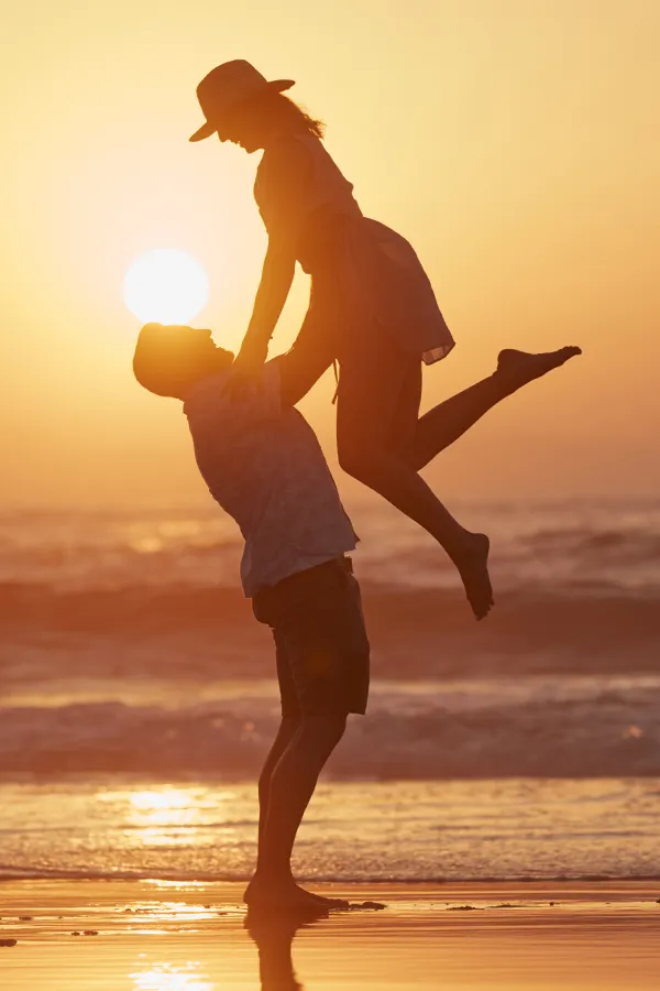 A man lifts a woman into the air on the beach. Get treatment for LCL tears from ProCare Wellness Institute in Virginia Beach.