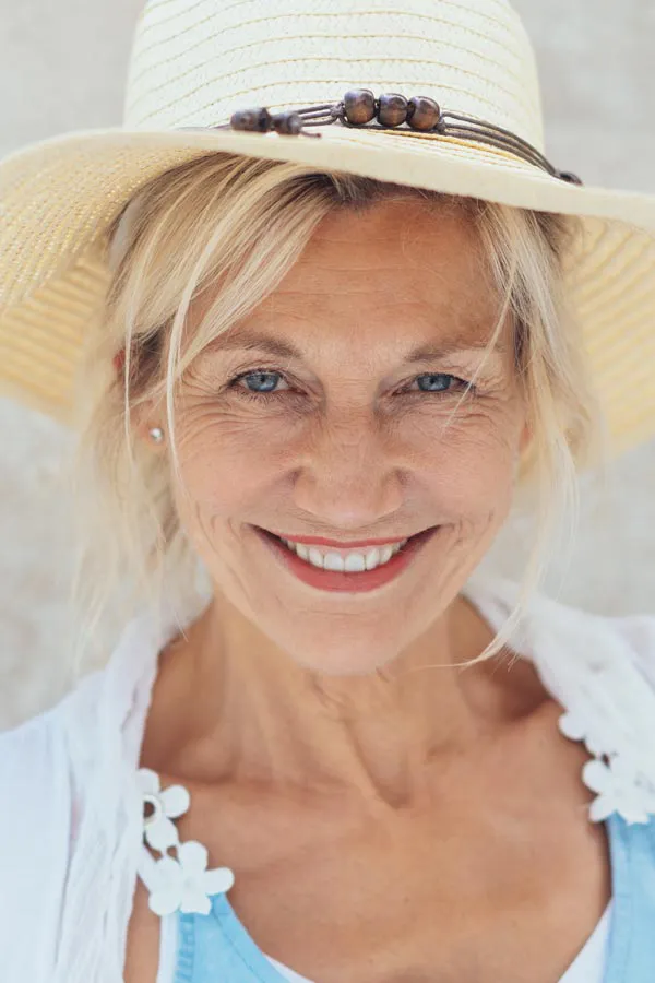 A beautiful, smiling older woman with blonde hair and a sunhat, happy with menopause treatment from ProCare Wellness Institute in Virginia Beach.