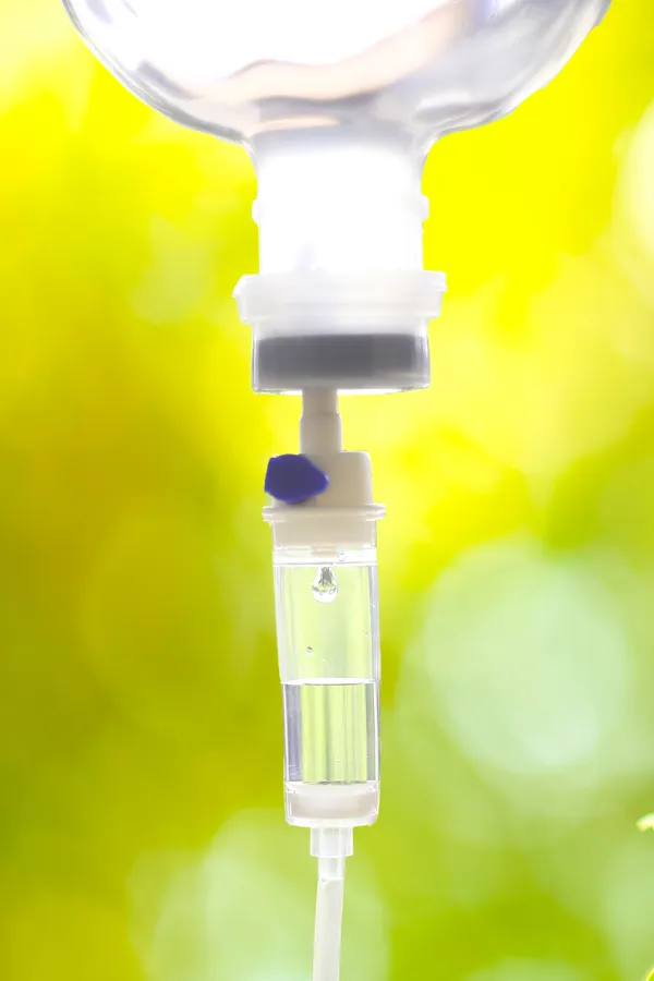 Close up of an IV drip with a lush, green background. Get NAD Therapy from ProCare Wellness Institute in Virginia Beach.