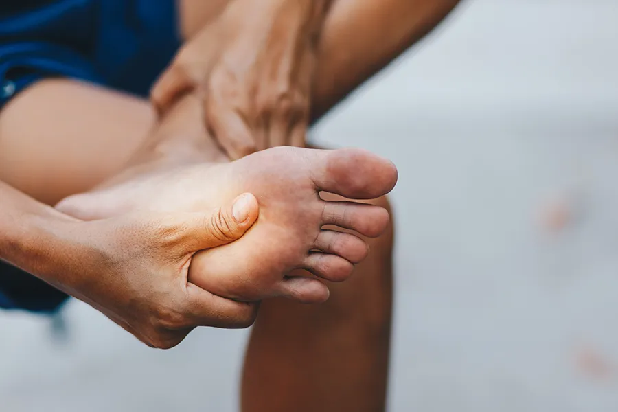 A man holds his foot in pain. Get neuropathy and nerve pain treatment from ProCare Wellness Institute in Virginia Beach.