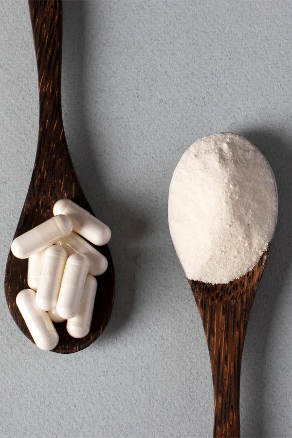 Two wooden spoons on a table, on with white powder and one with capsules, representing peptide therapy from ProCare Wellness Institute in Virginia Beach.
