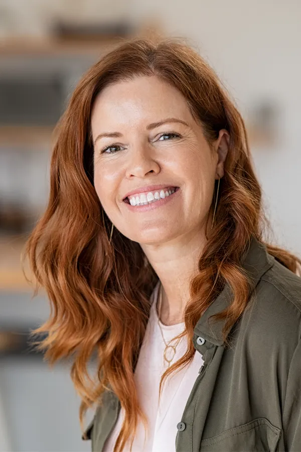 A woman with beautiful long red hair smiles due to the success of peptides for hair restoration treatments from ProCare Wellness Institute in Virginia Beach.
