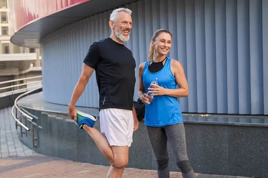 A middle-aged couple happily stretch and prepare for exercise after receiving effective peptide therapy for healing and recovery from ProCare Wellness Institute in Virginia Beach.