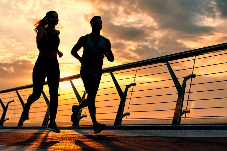A couple jogging on a bridge at sunrise, representing performance enhancing peptide therapy from ProCare Wellness Institute in Virginia Beach.
