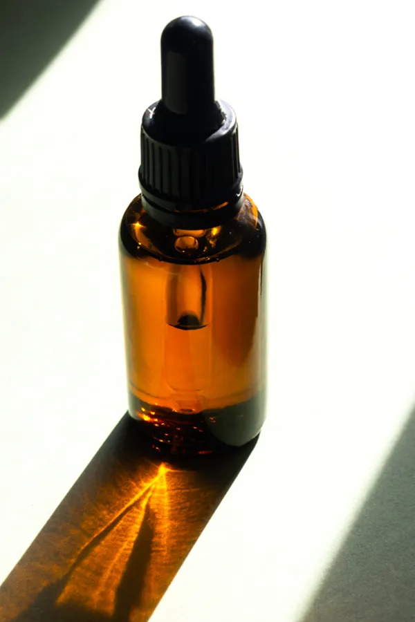 A brown dropper bottle on a table lit by sunlight, representing performance enhancing peptide treatment from ProCare Wellness Institute in Virginia Beach.