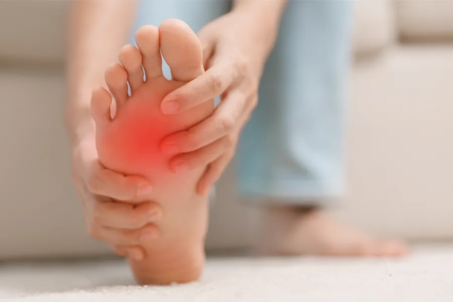 A woman holds her foot in pain. Schedule plantar fasciitis treatment from ProCare Wellness Institute in Virginia Beach.