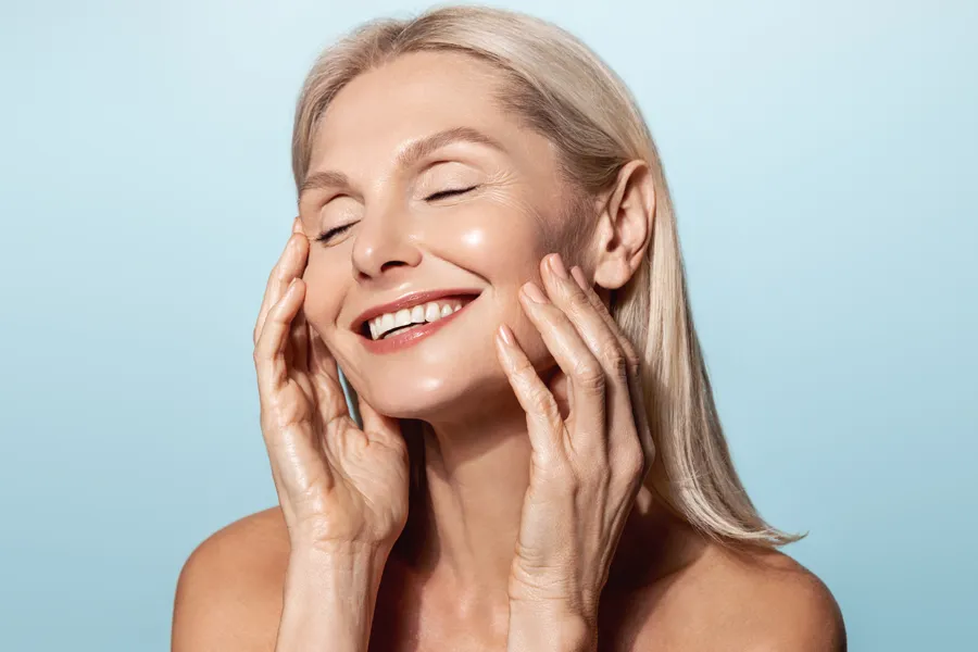 A woman with a smooth, tight jawlline smiles and holds her face. Schedule Radiofrequency Microneedling for Face and Jawline Skin Treatment from ProCare Wellness Institute in Virginia Beach.