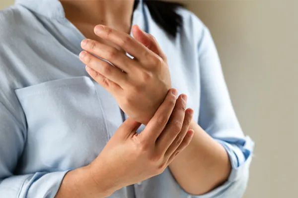 Close up of a woman in a blue blouse rubbing her wrist. Get rheumatoid arthritis treatment from ProCare Wellness Institute in Virginia Beach.