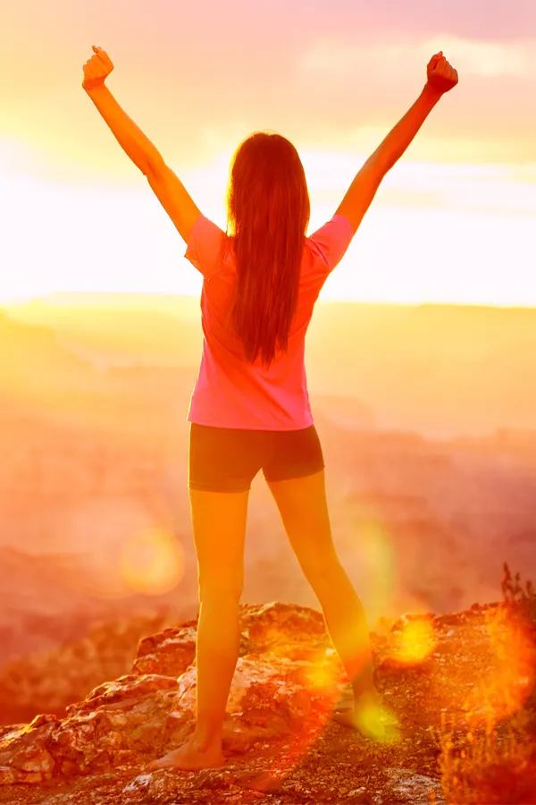 A woman raises her arms on a hilltop. Get rotator cuff treatment from ProCare Wellness Institute in Virginia Beach.