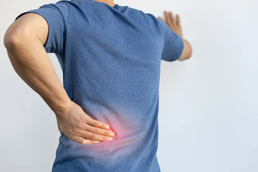 Sciatica-Clinic A man holds his lower back in pain. Schedule sciatica treatment from ProCare Wellness Institute in Virginia Beach.
