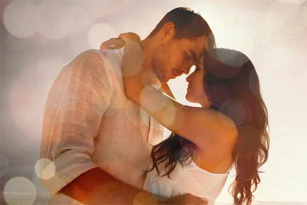 A couple in linen shirts standing in a sparkling light embraces each other with their foreheads touching and eyes closed, happy with their sexual wellness treatments from ProCare Wellness Institute in Virginia Beach.