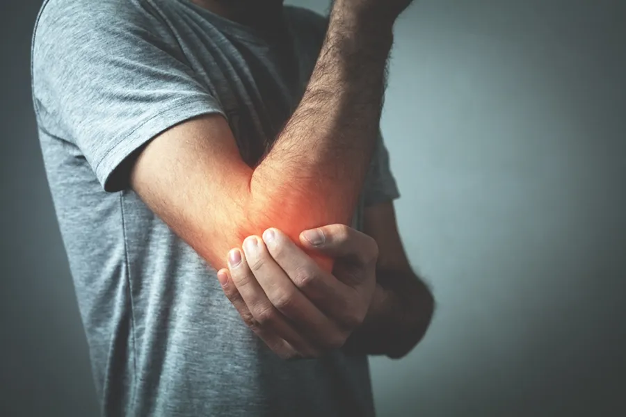 A man holds his elbow in pain. Schedule tennis elbow treatment from ProCare Wellness Institute in Virginia Beach.