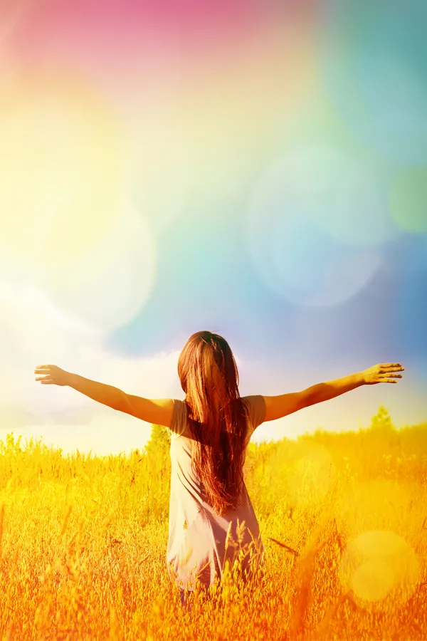 A woman stands in a field with her arms outstretched. Get tennis elbow treatment from ProCare Wellness Institute in Virginia Beach.