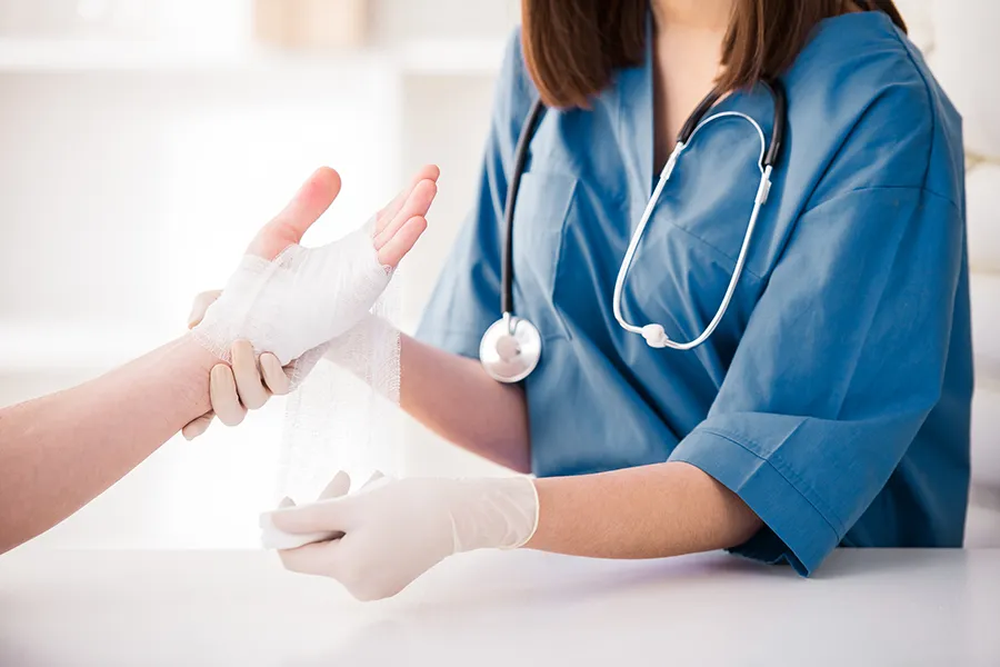 A doctor treats a bandage on a patient's hand. Get wound care treatment from ProCare Wellness Institute ion Virginia Beach.